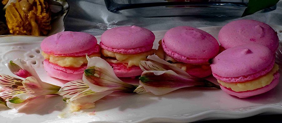 A white plate topped with pink macarons and flowers.