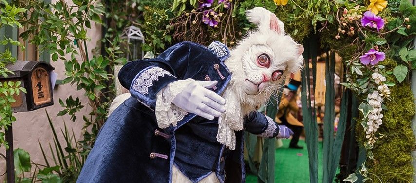 Rabbit welcoming guests to sweet 16 alice in wonderland party 