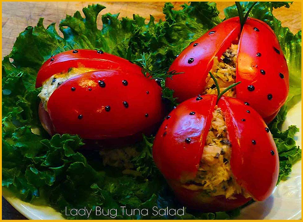 Three tomatoes stuffed with tuna are on a plate with lettuce