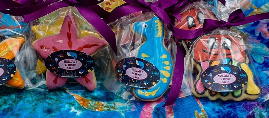 A bunch of cookies are wrapped in plastic and tied with purple ribbons.