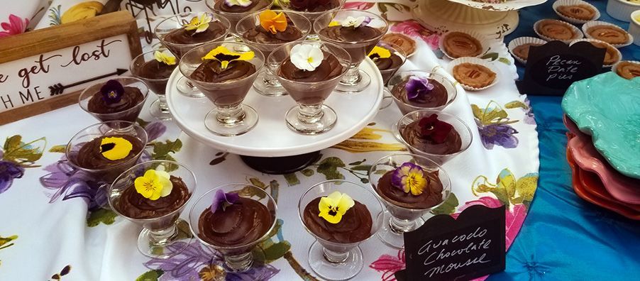 A table topped with a variety of desserts and flowers.