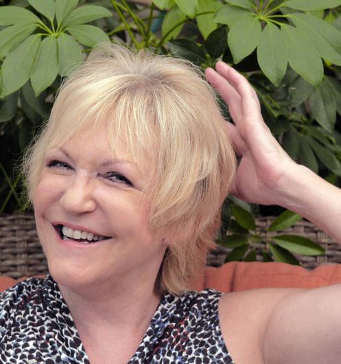 A woman in a leopard print shirt is smiling and touching her hair