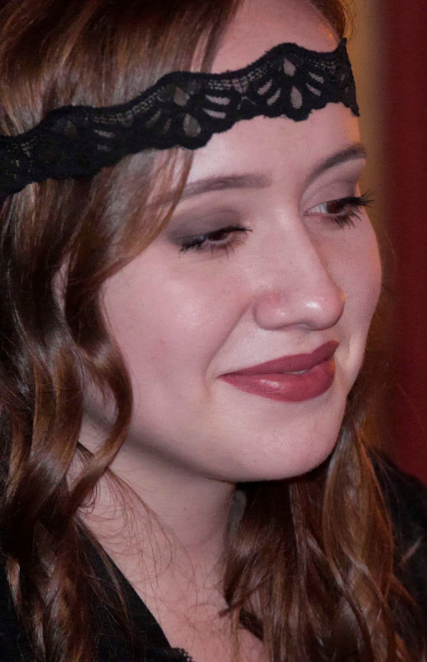 A woman wearing a black lace headband is smiling.