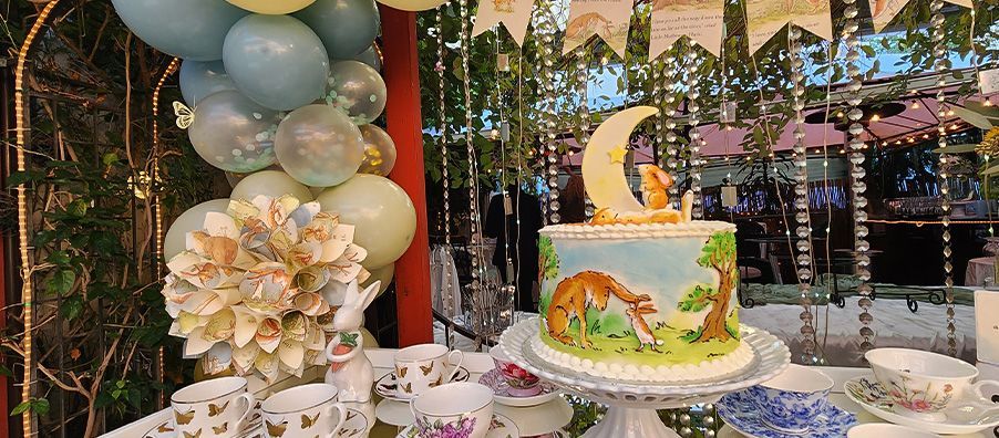 Guess How Much I Love You cake with balloon garland backdrop in bexx secret garden
