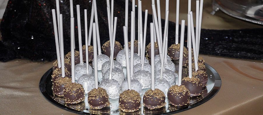 A plate of cake pops on sticks on a table
