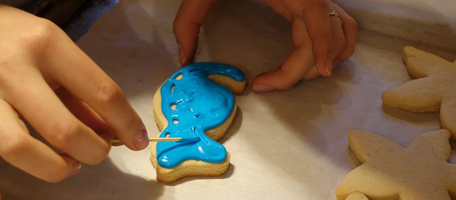 A person is decorating a cookie with blue frosting.