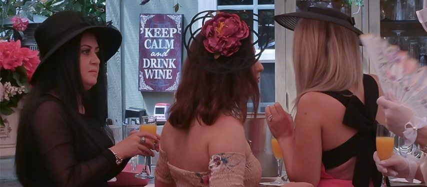 Three women are sitting at a table drinking wine.