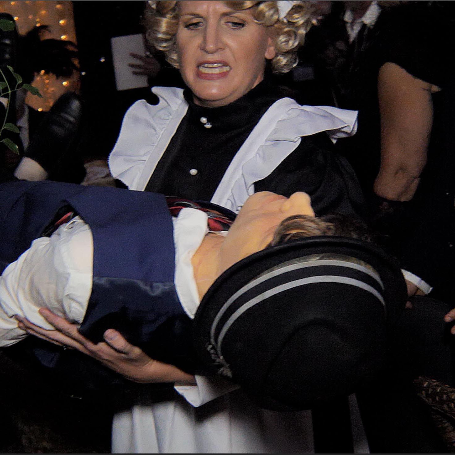 A woman in a maid costume is carrying a man in a suit