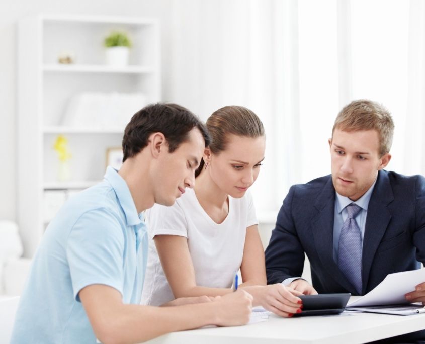 A man and a woman are sitting at a table with a man in a suit.