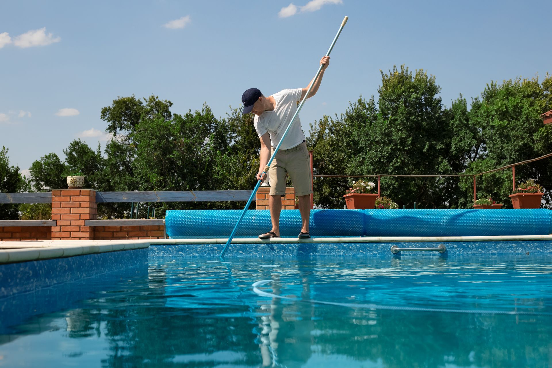 A man is cleaning a swimming pool with a mop