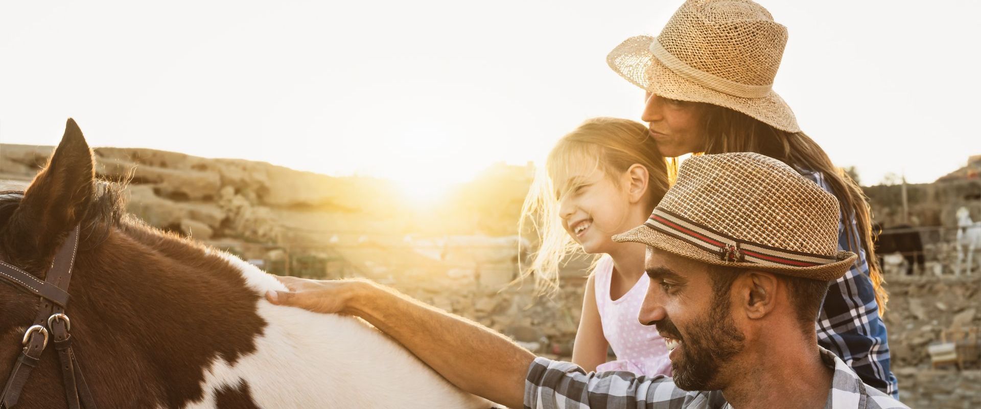 A man and woman are petting a horse while a little girl looks on.