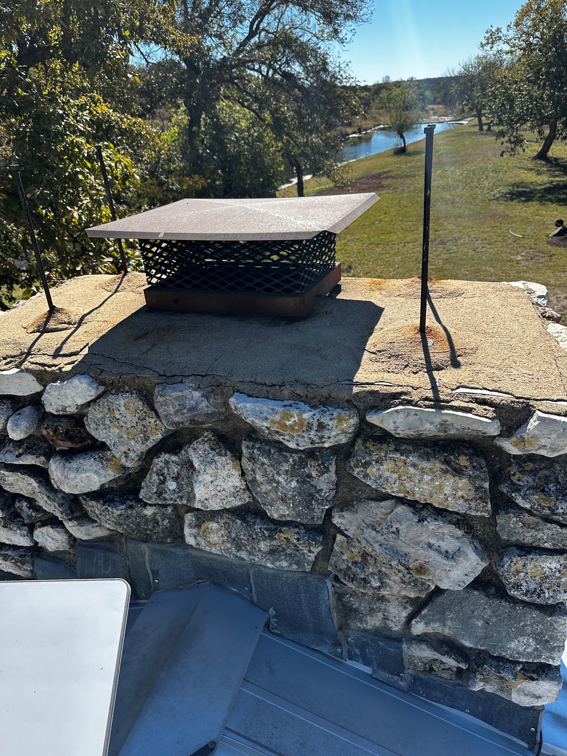 A chimney cap is sitting on top of a stone wall.