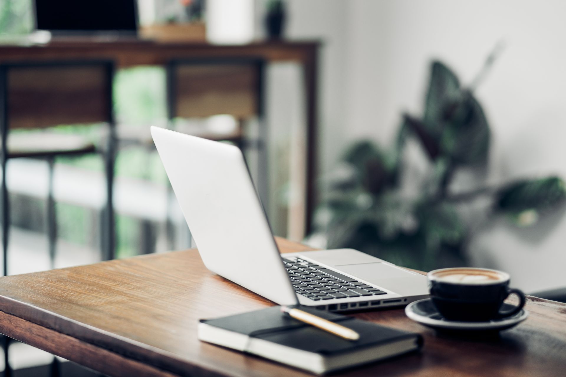 Laptop and coffee cup on a wooden table in a cozy cafe setting