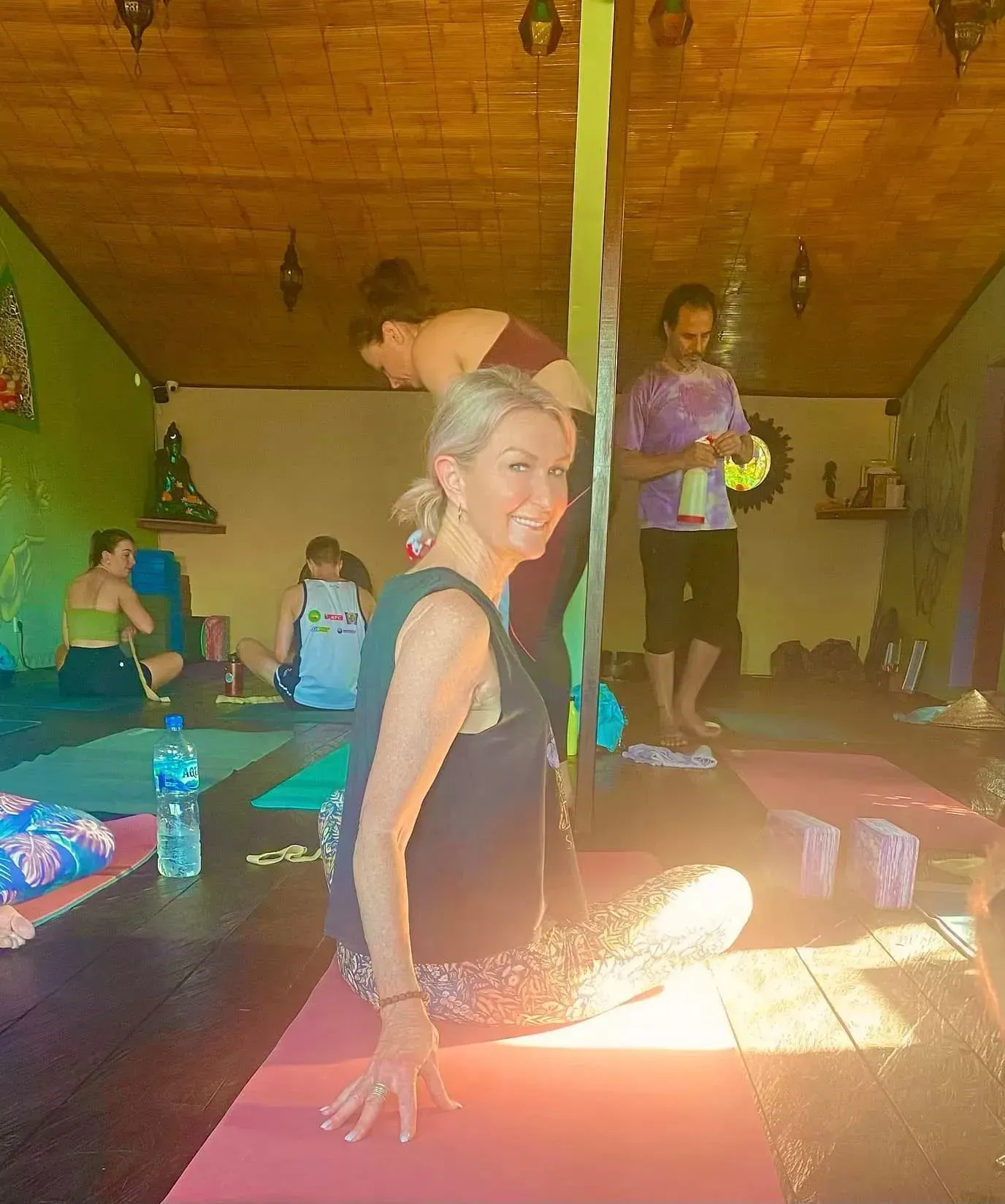 A group of people practicing yoga in a room with a low-angle view and candles on the floor in the foreground.