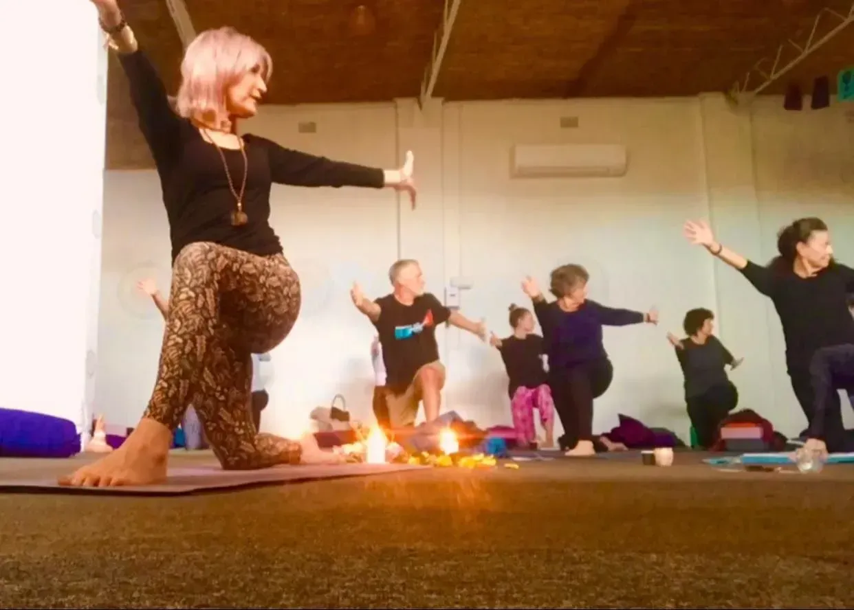 A group of people practicing yoga in a room with a low-angle view and candles on the floor in the foreground.