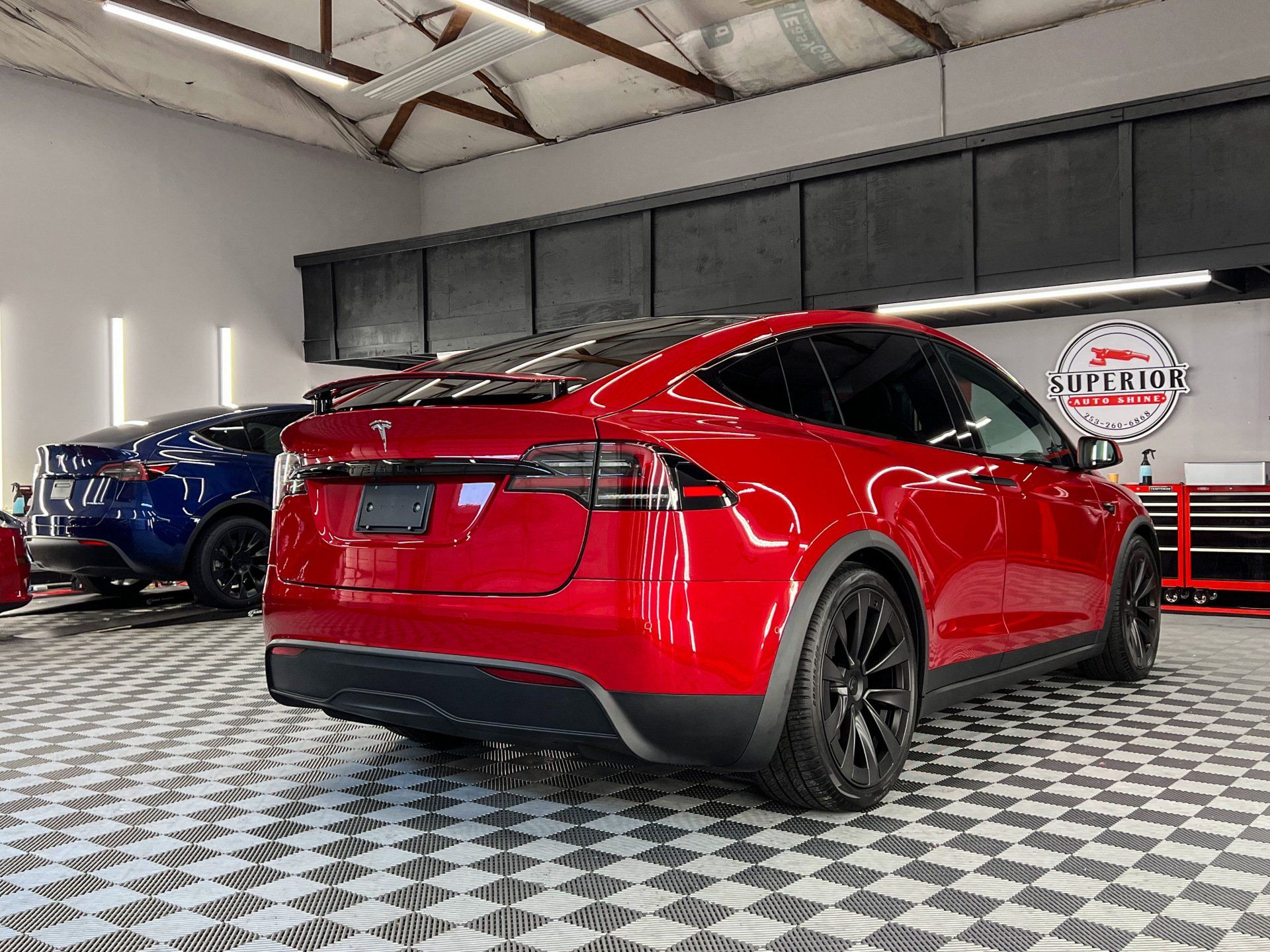 A red tesla model x is parked in a garage.