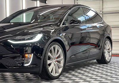 A black tesla model x is parked in a garage.