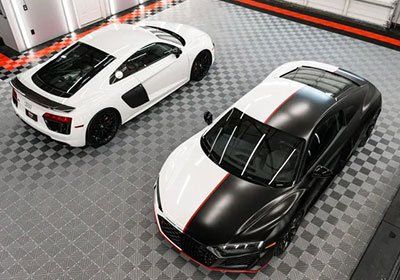 Two sports cars are parked next to each other in a garage.