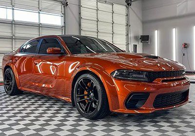 An orange dodge charger is parked in a garage.