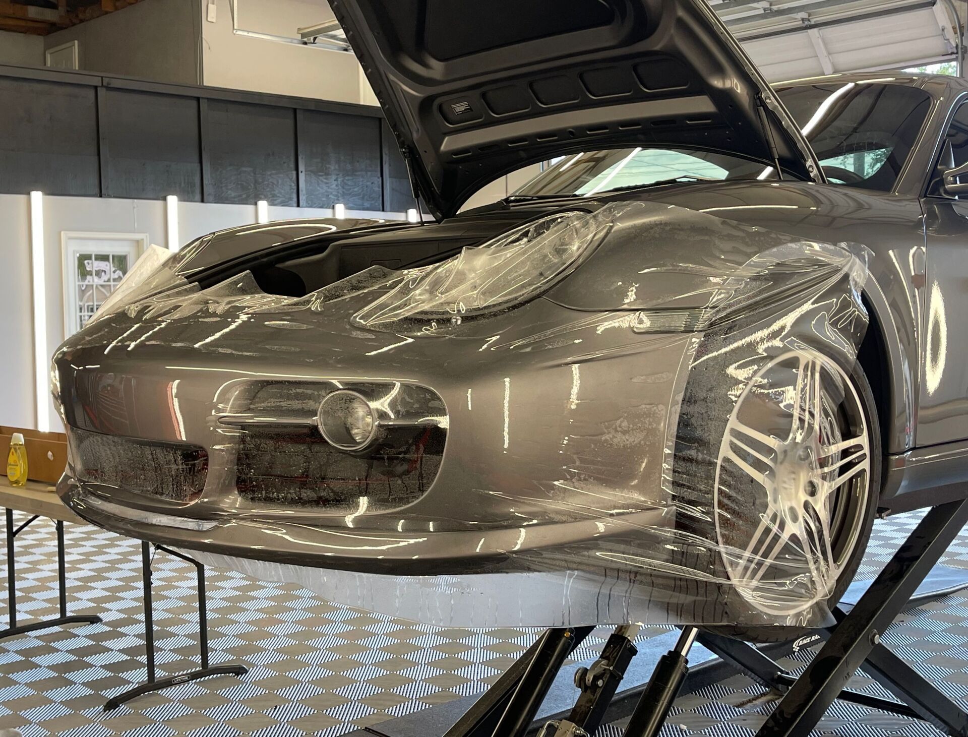 A car is sitting on a lift with its hood open.