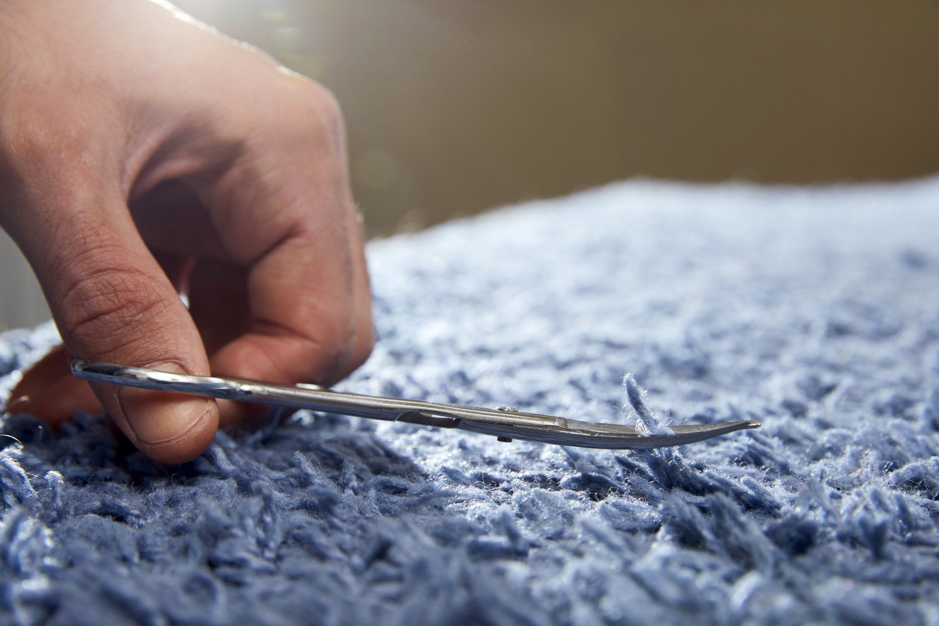 Closeup of hand cutting off string on a carpet with scissors. Carpet cleaning service