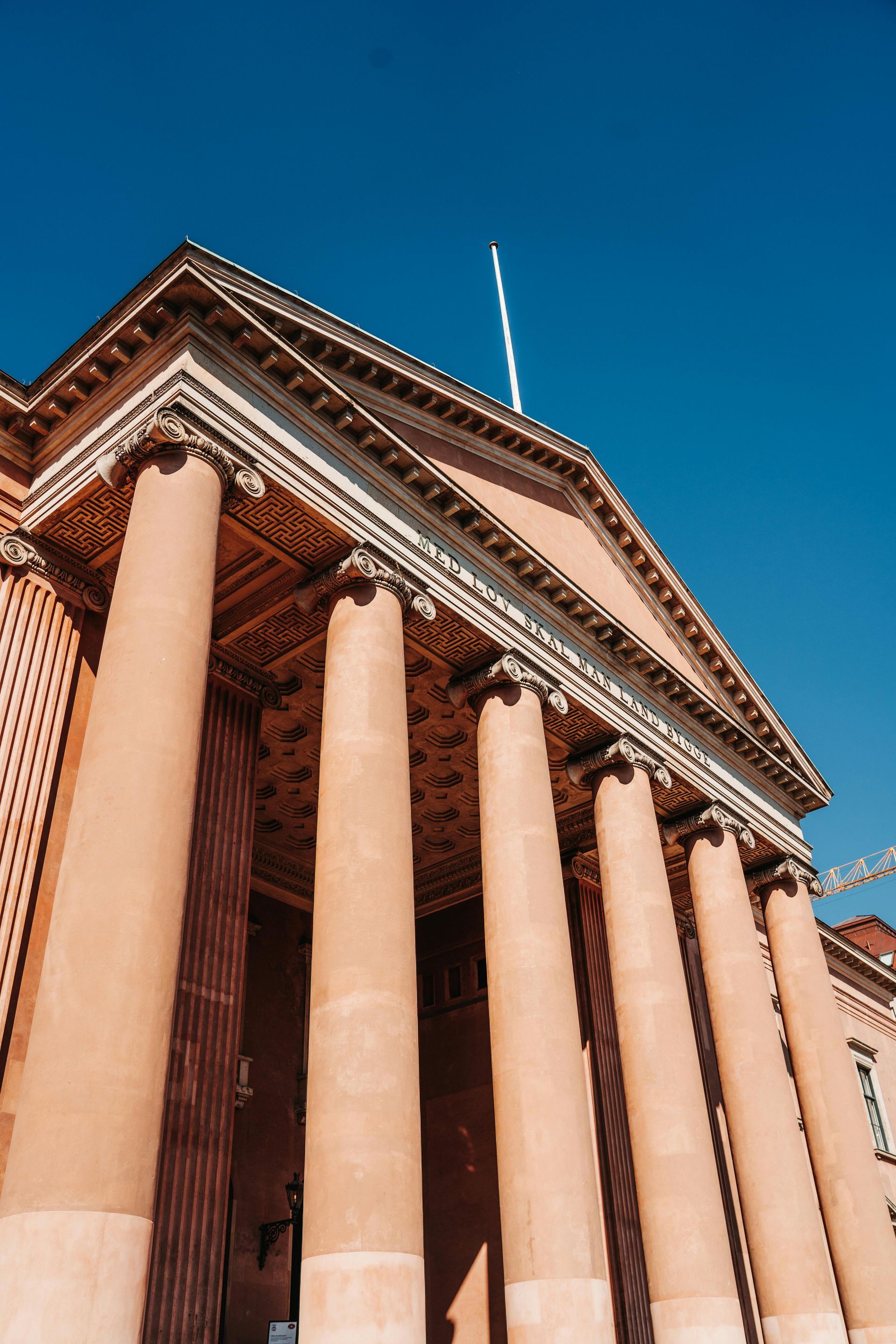 A large building with columns and a flag on top of it.