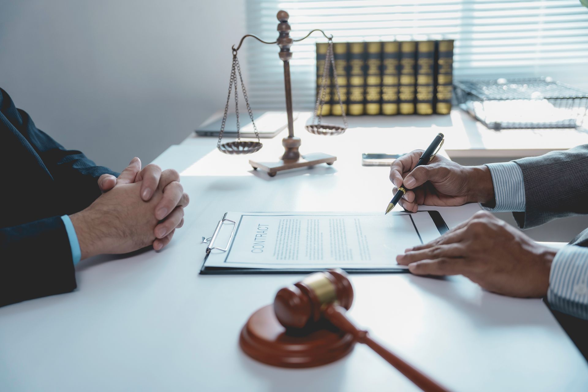 Legal professional reviewing a contract with a client, with a gavel and scales of justice.