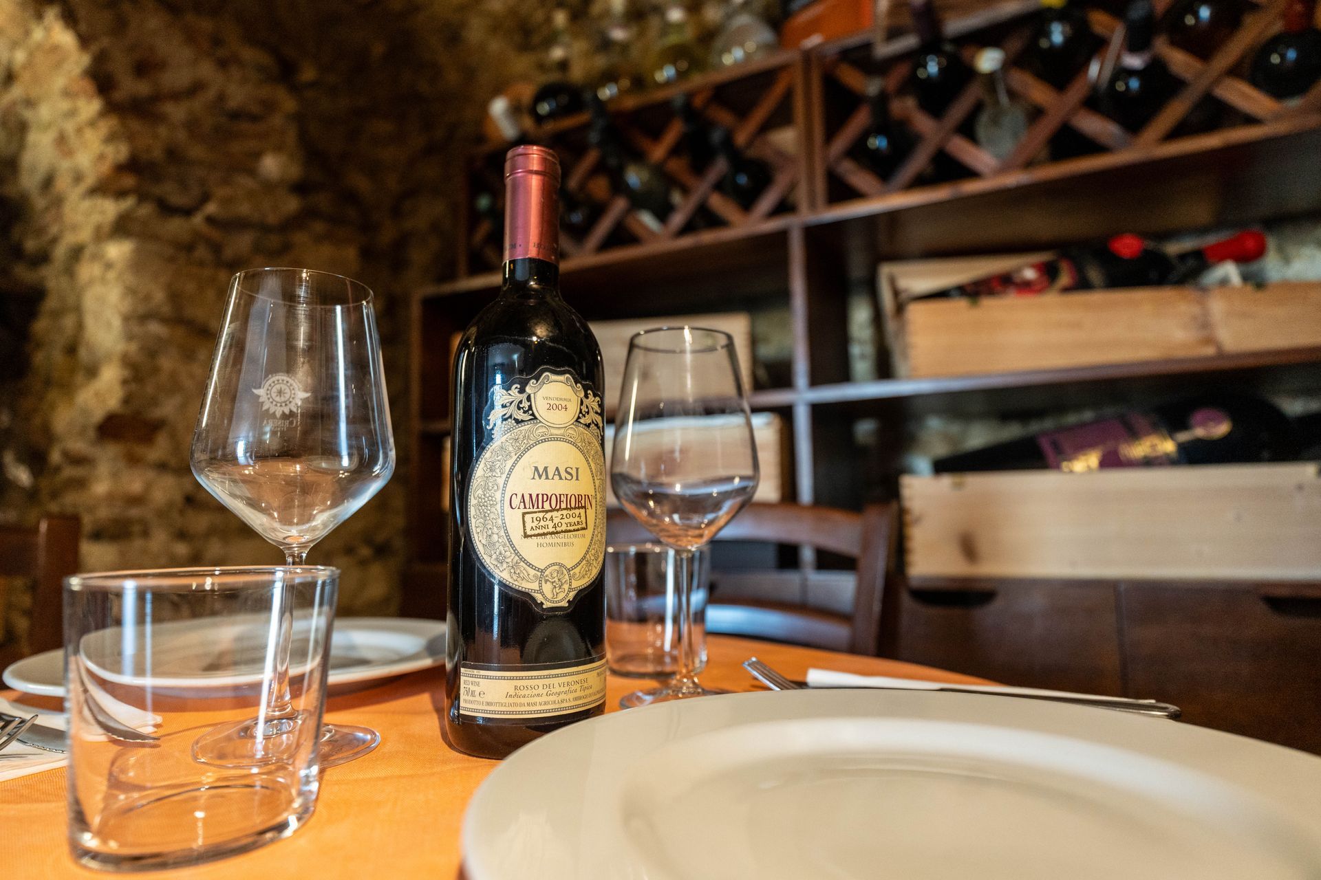 Una bottiglia di vino è appoggiata su un tavolo accanto a due bicchieri da vino