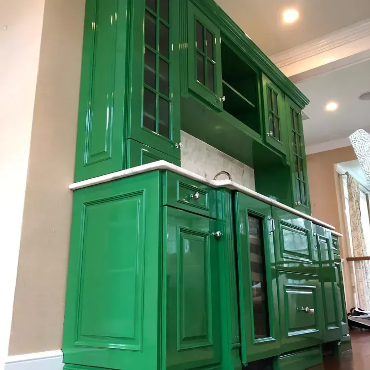 Green kitchen cabinets with a white countertop and glass-front upper cabinets.