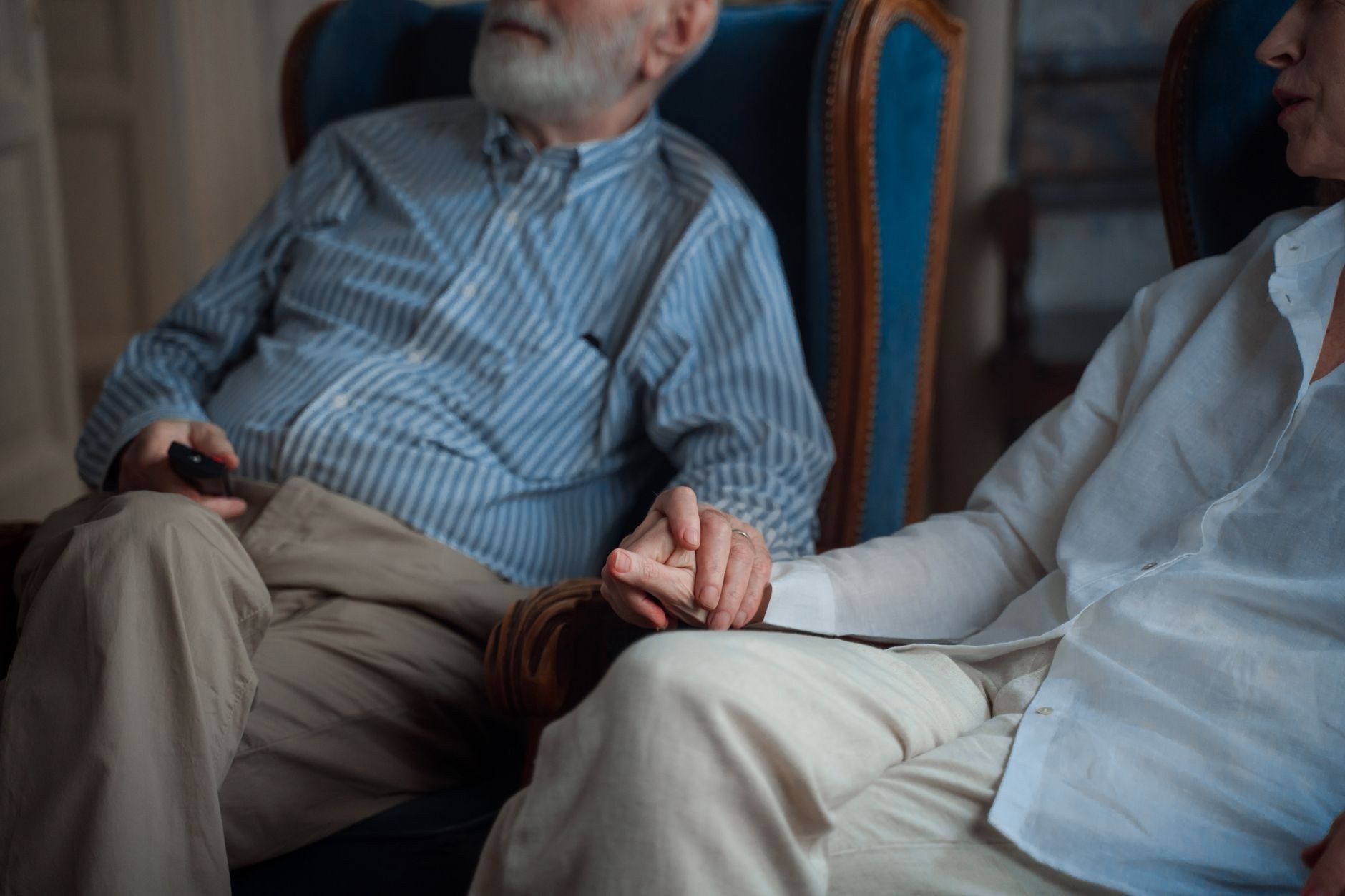 An older man and a younger woman sit indoors near a window in a quiet, thoughtful conversation about funeral planning.