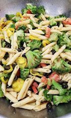 Pasta penne with broccoli and tomatoes in a pan, mixed with light sauce and herbs