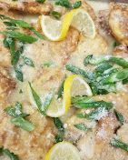 Close-up of a golden baked fish dish with lemon slices and green herbs