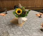 Sunflower bouquet in a white vase on a dining table with folded napkins and candles