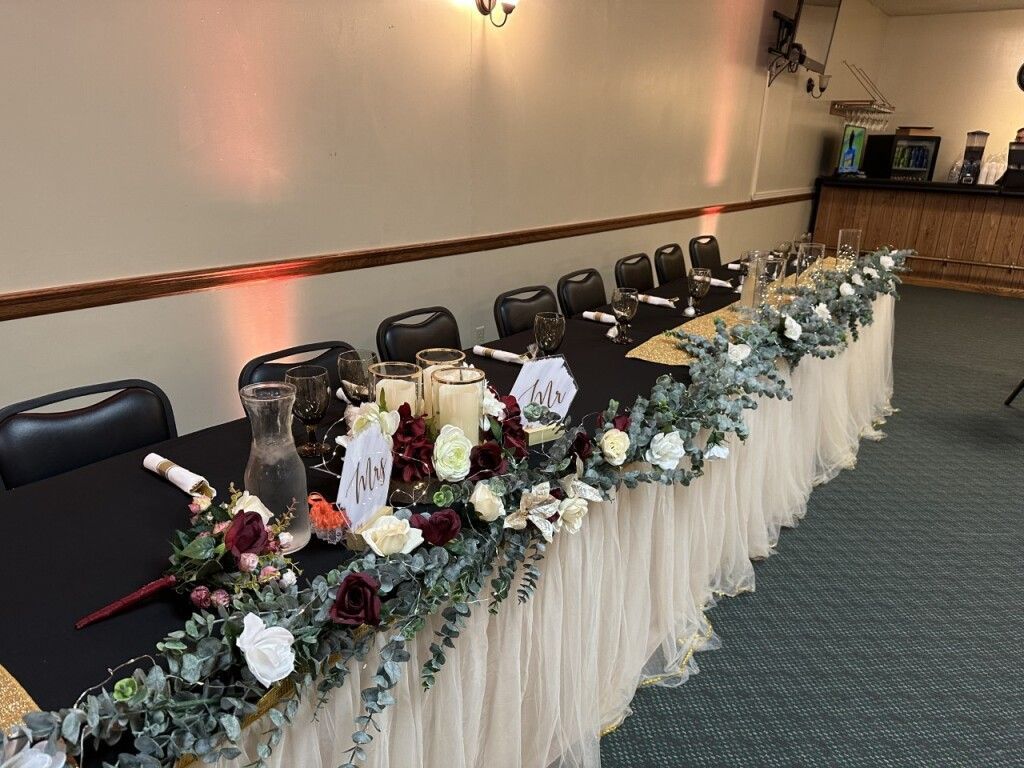 Decorated banquet table with flowers and candles along a wall in a conference room
