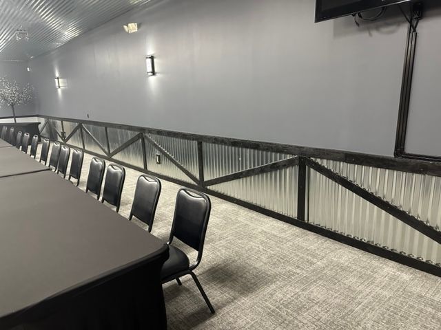 Empty conference room with long table, black chairs, and gray walls with wall lights