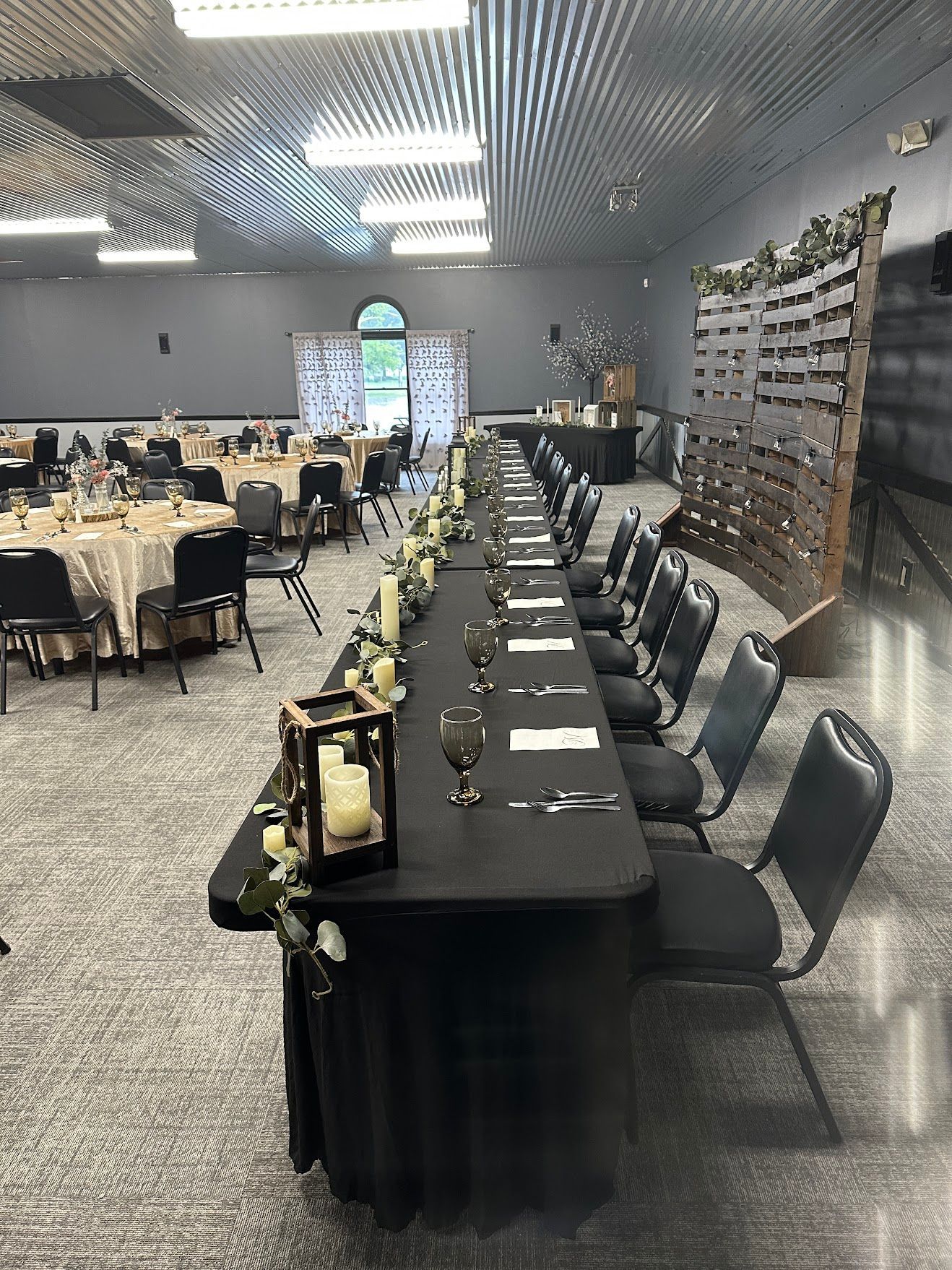 Banquet hall with long black-draped tables, place settings, and chairs arranged for an event