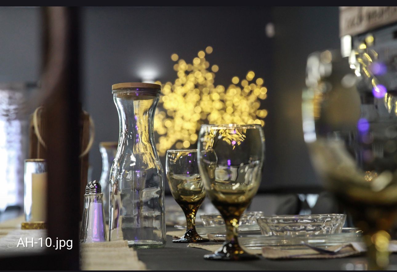 Wine glasses and a carafe on a table, with warm bokeh lights in the background.