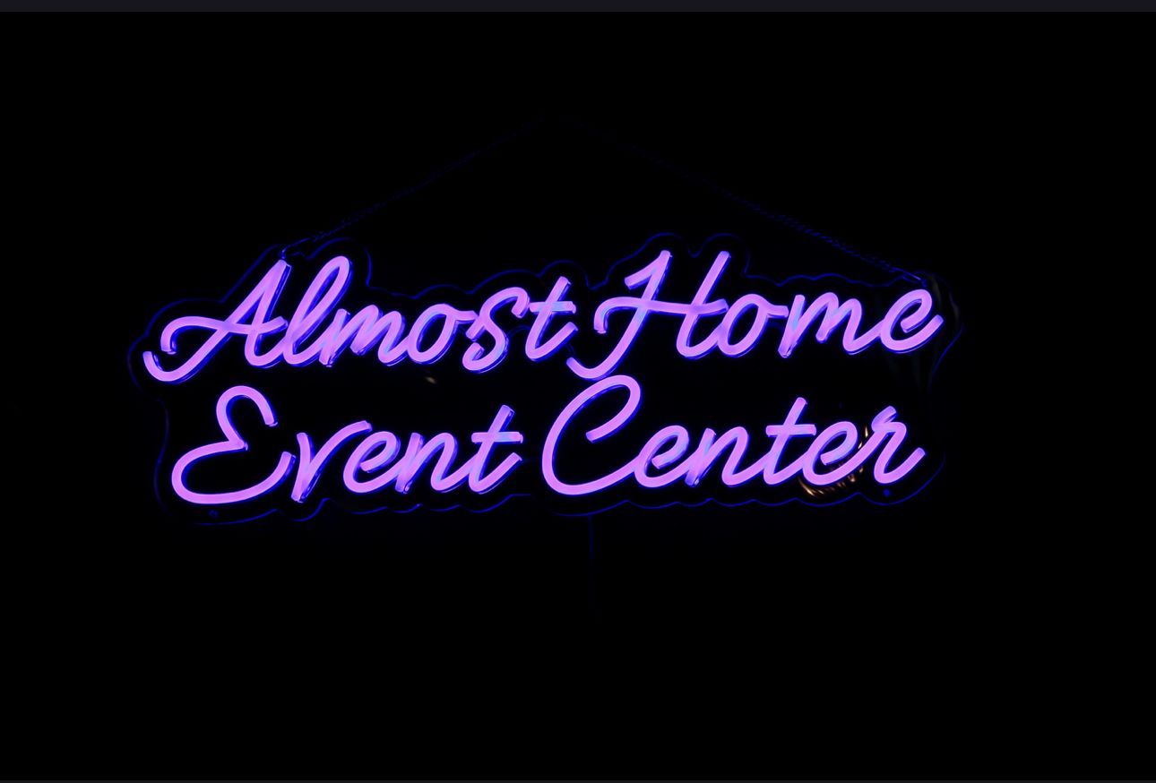 Neon purple script reading “Almost Home Event Center” on a black background