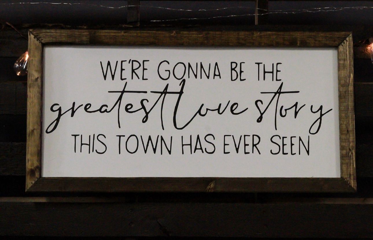 Framed sign reading “We’re gonna be the greatest love story this town has ever seen”