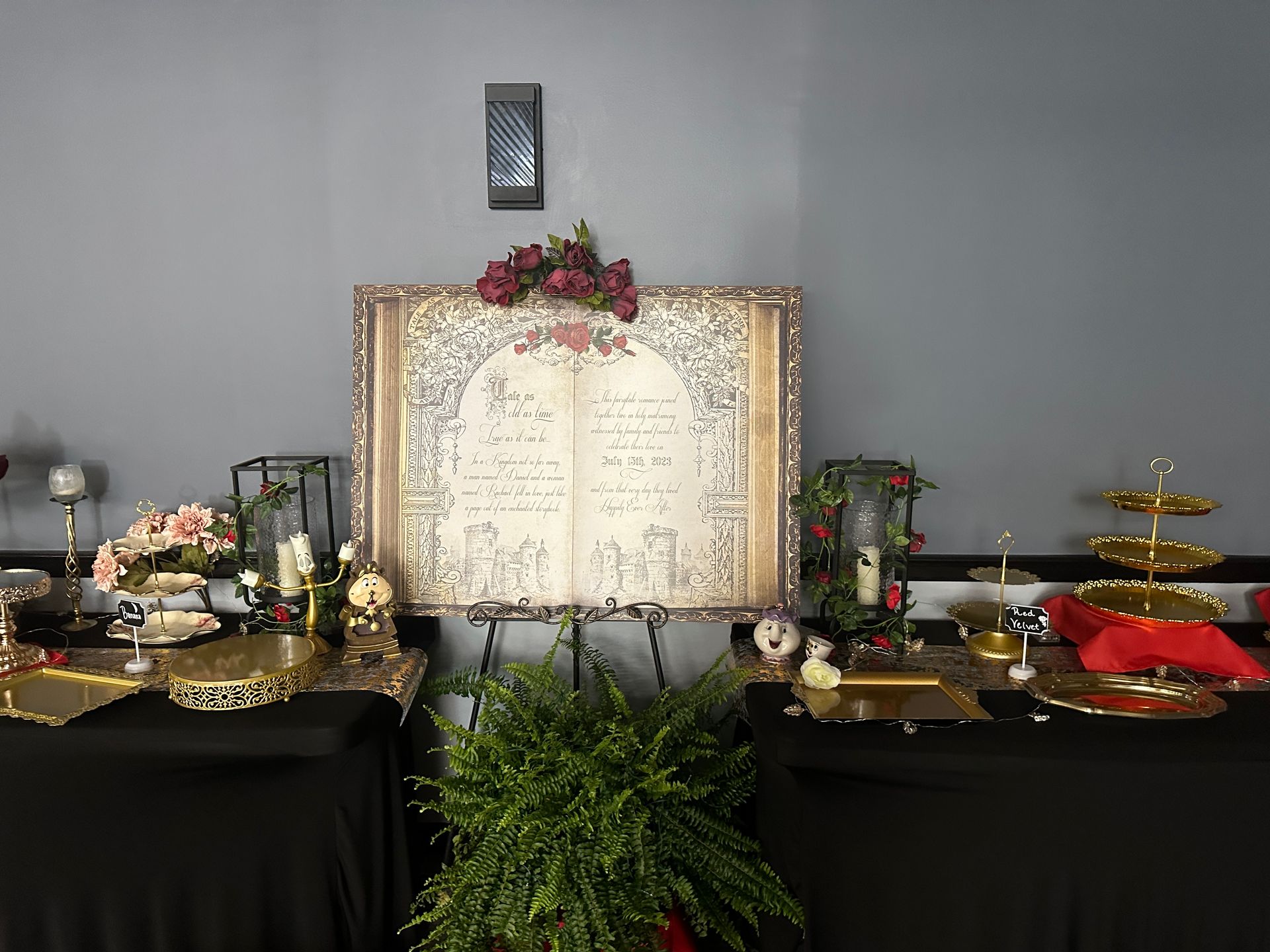 Decorated memorial altar with open guestbook, flowers, candles, and gold trays on black-draped tables