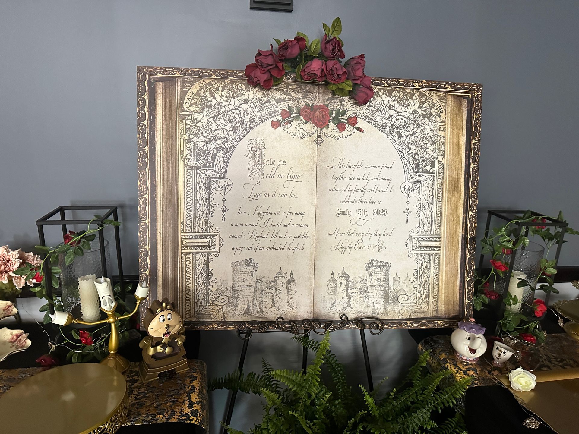 Decorative memorial display with framed sign, flowers, candles, and gold accents on a table