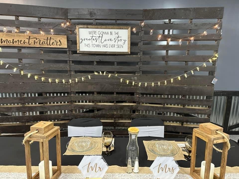 Rustic charcuterie display on a wooden pallet wall with serving trays, lanterns, and string lights