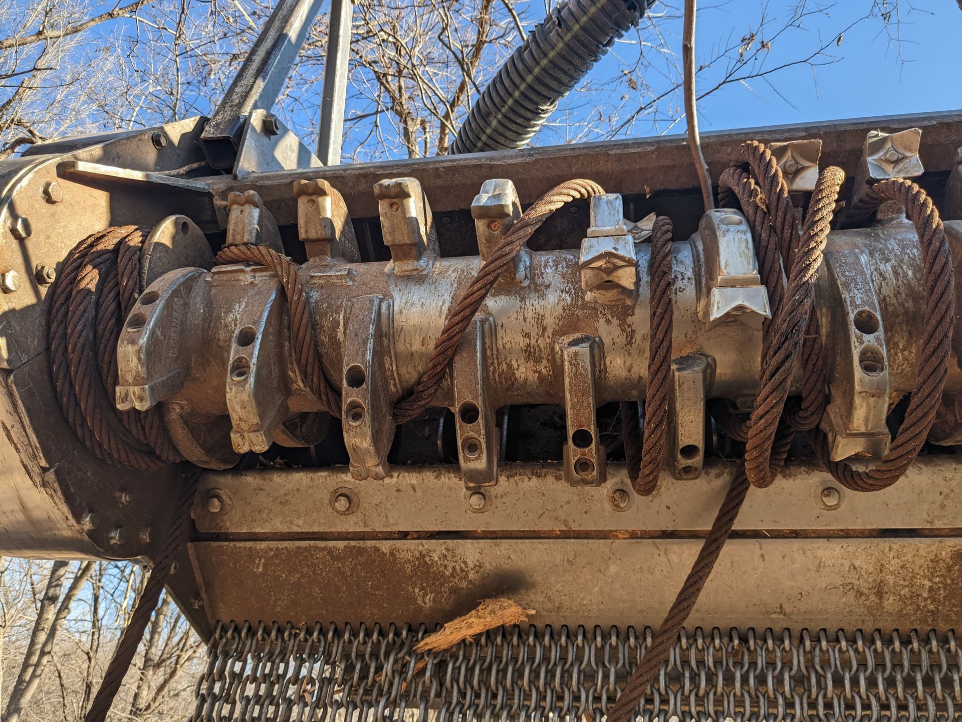 Rusty industrial machine with large rotating drum and metal spikes outdoors