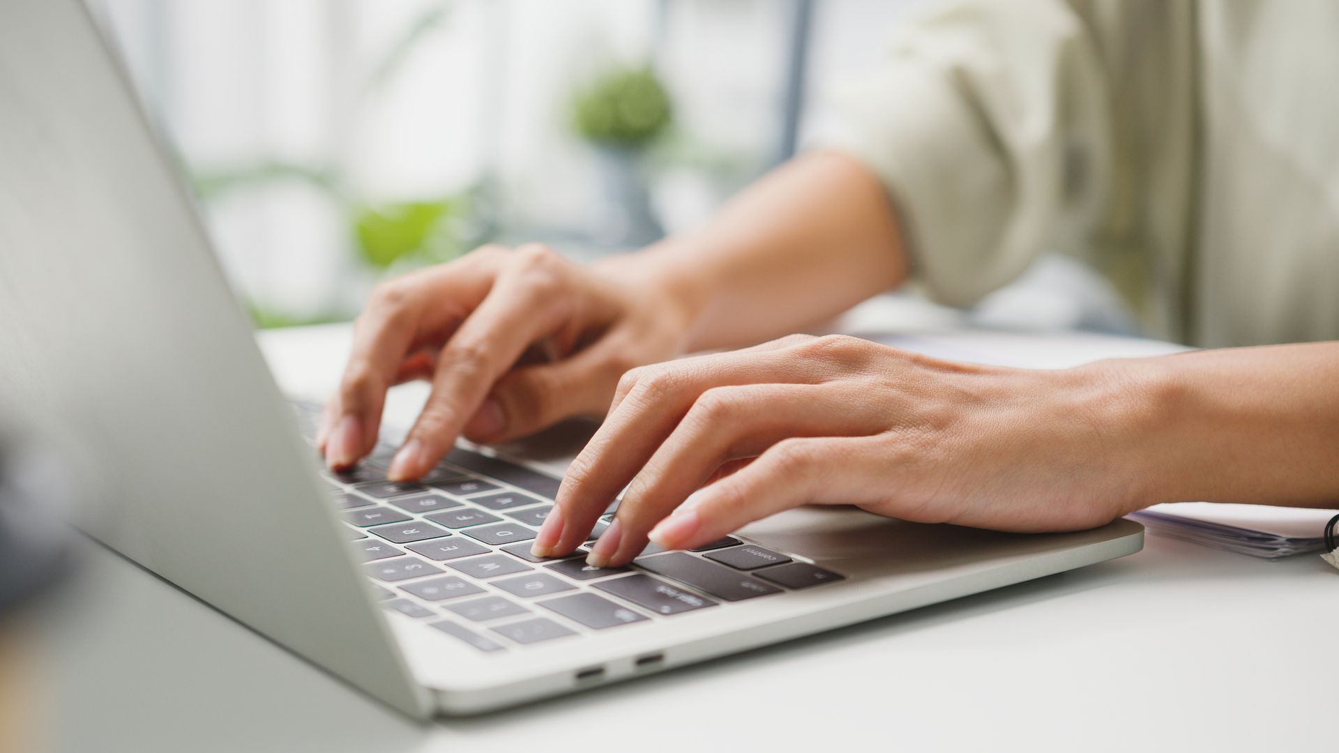 a person's hands typing on a laptop