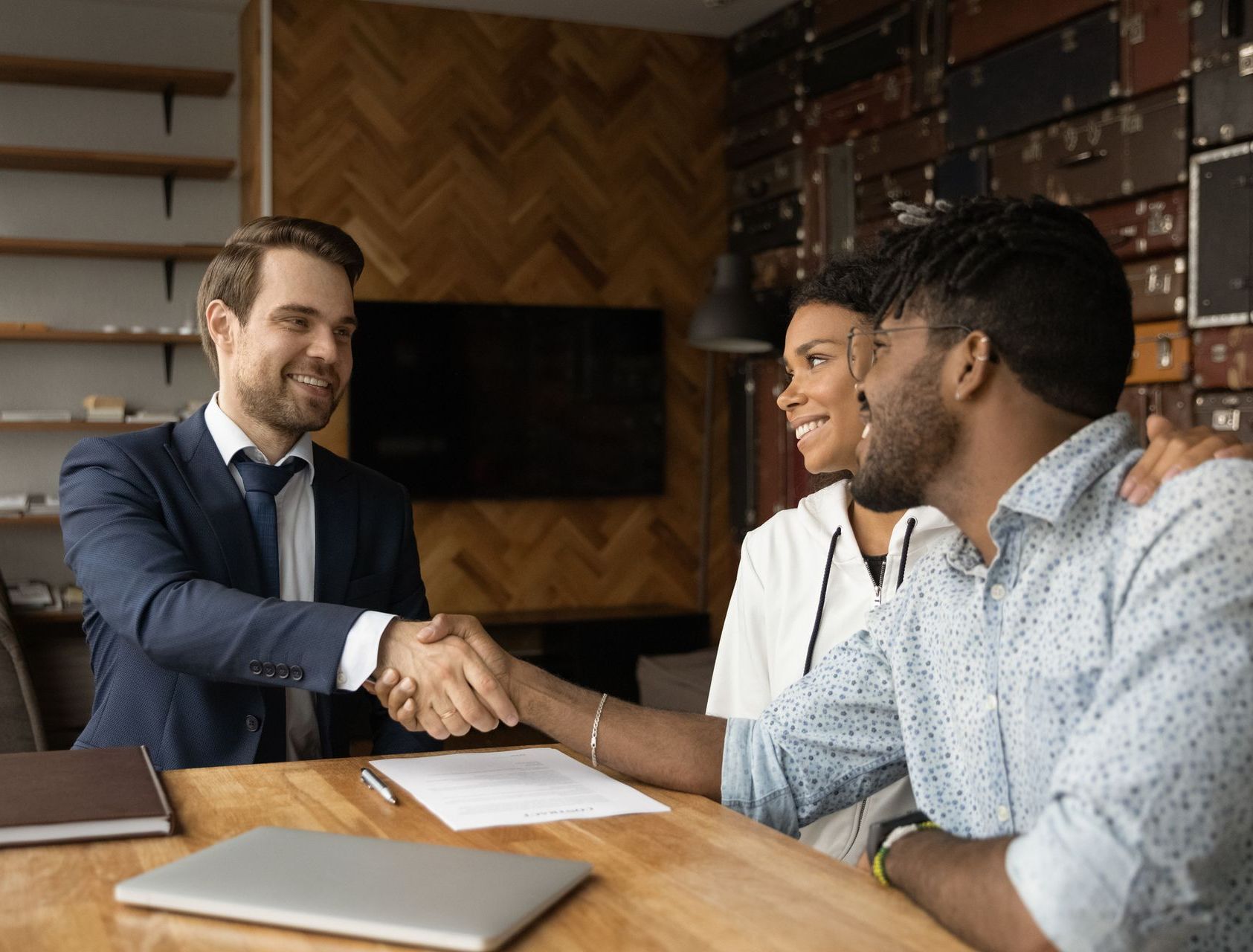 A man is shaking hands with a couple while sitting at a table.