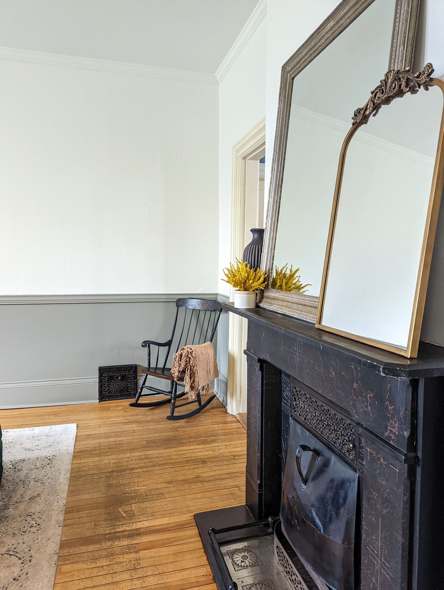 A living room with a fireplace , rocking chair , and mirror.