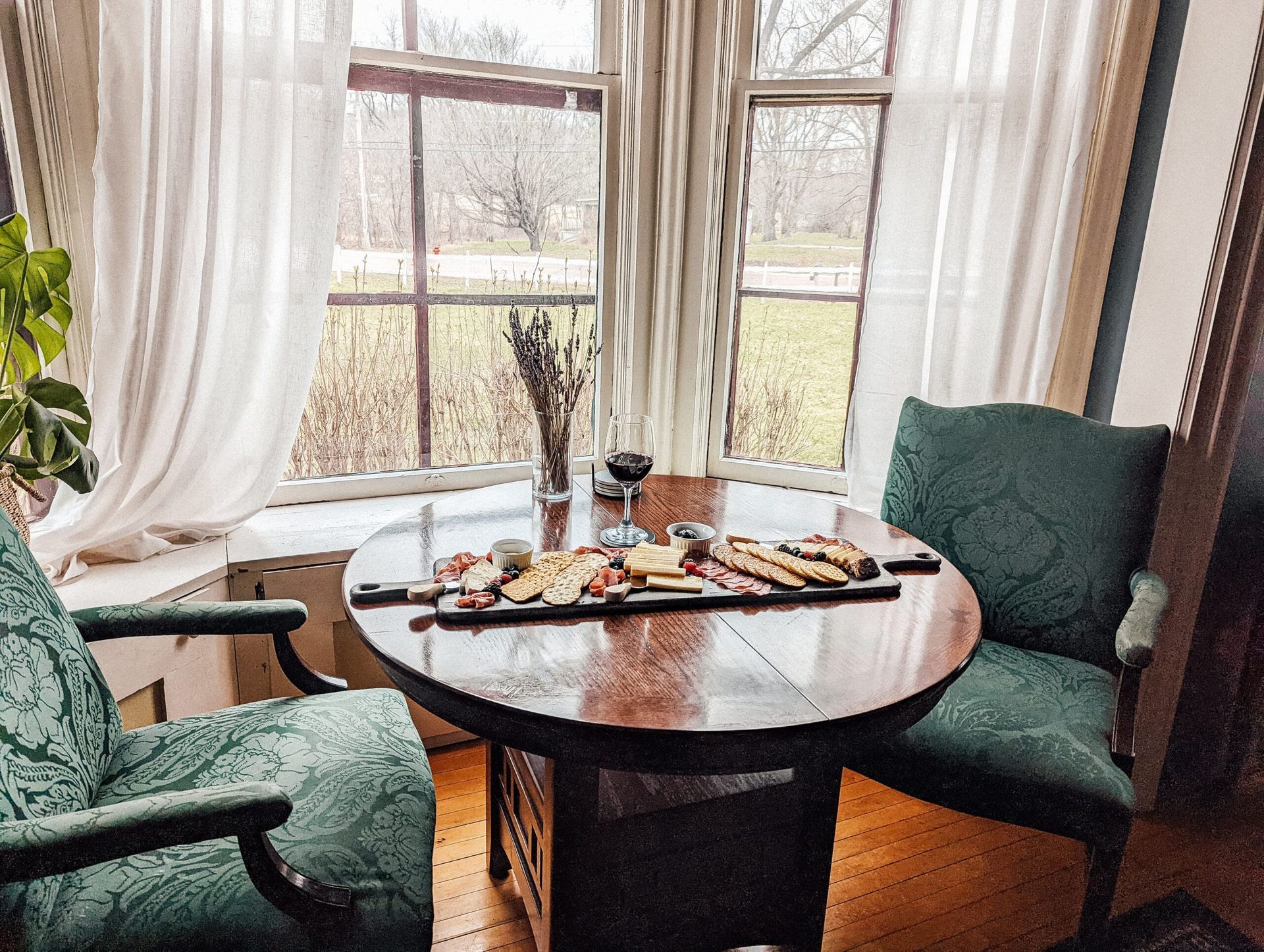 A round table with two chairs in front of a window.