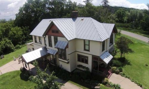 An aerial view of a large white house with a metal roof