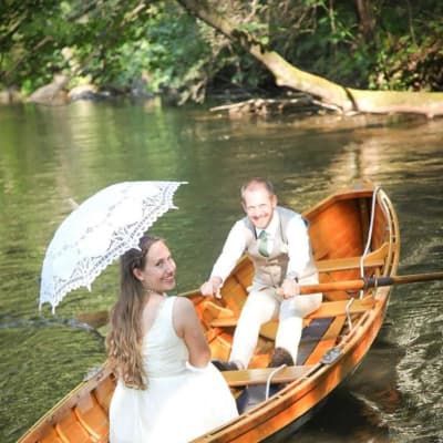 A bride and groom are in a boat on a lake