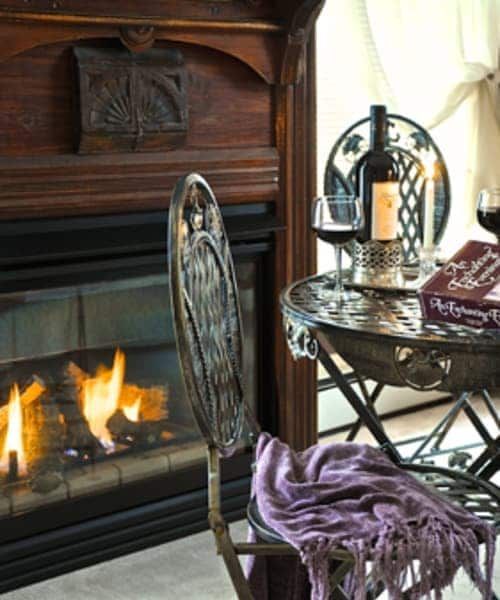 A bottle of wine sits on a table in front of a fireplace